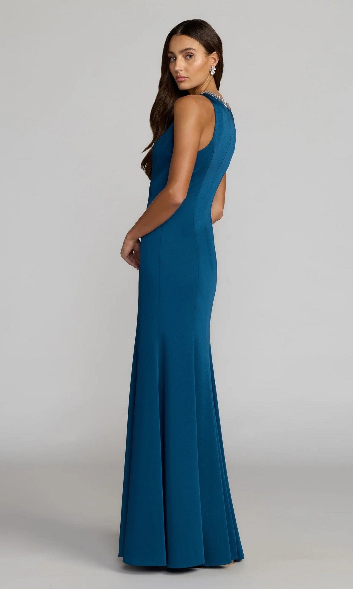 Woman wearing the Mac Duggal 49093 Beaded-Neck Long Prom Dress—a floor-length, sleeveless teal gown with a fitted bodice—standing sideways against a plain background.